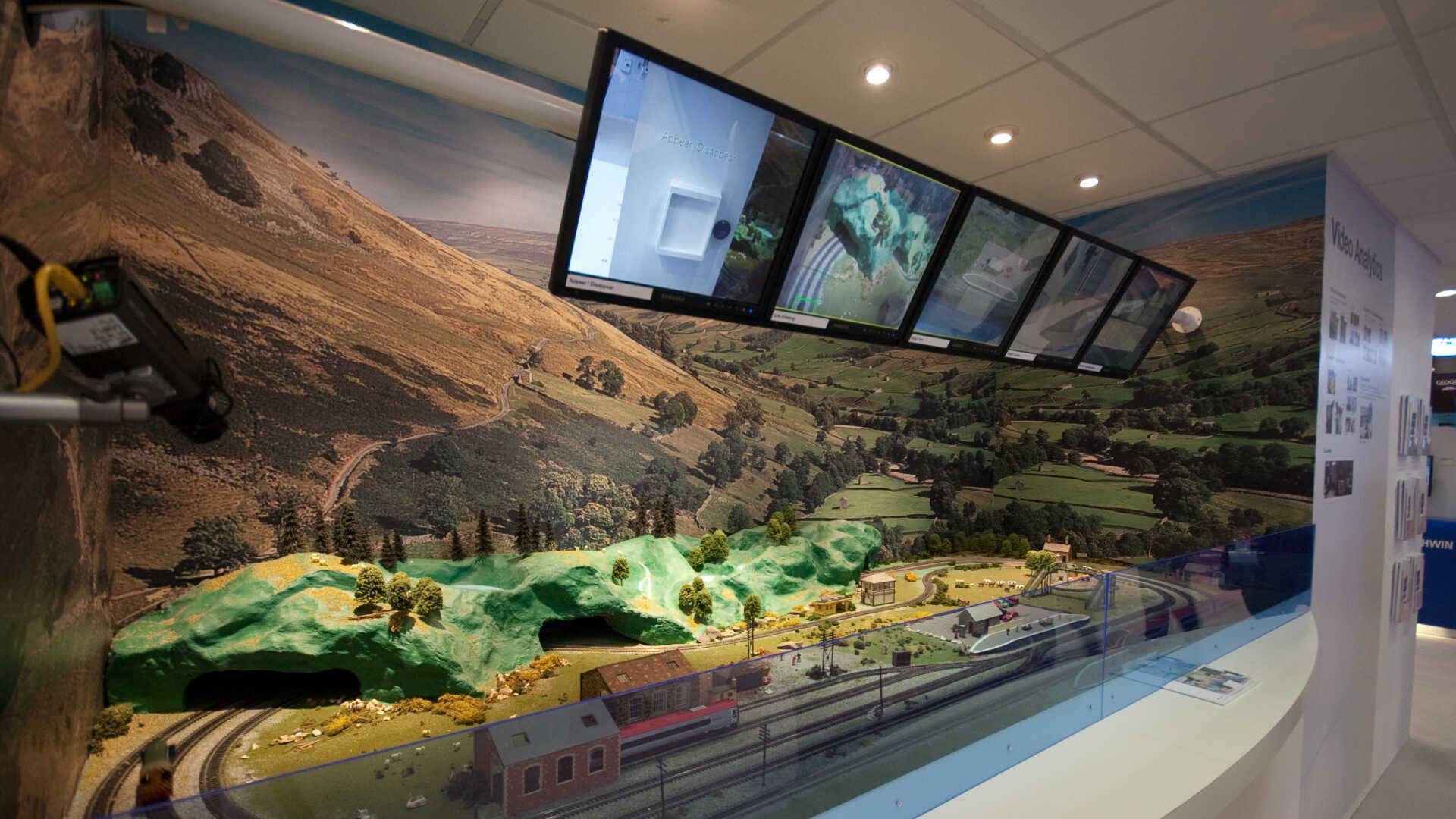 informative screens above a model train track