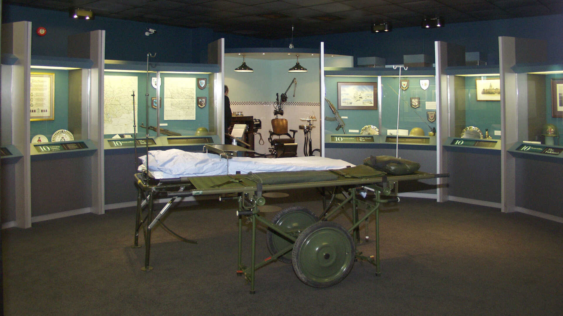 military hospital bed displayed next to display cases