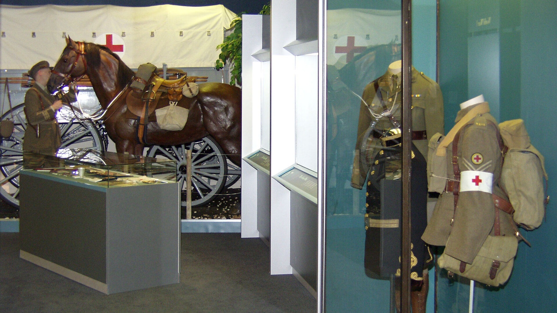 soldier and horse mannequins beside a glass case containing army uniform